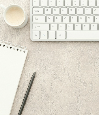 Vue de haut sur un clavier, un café, un cahier de notes et un crayon sur une table